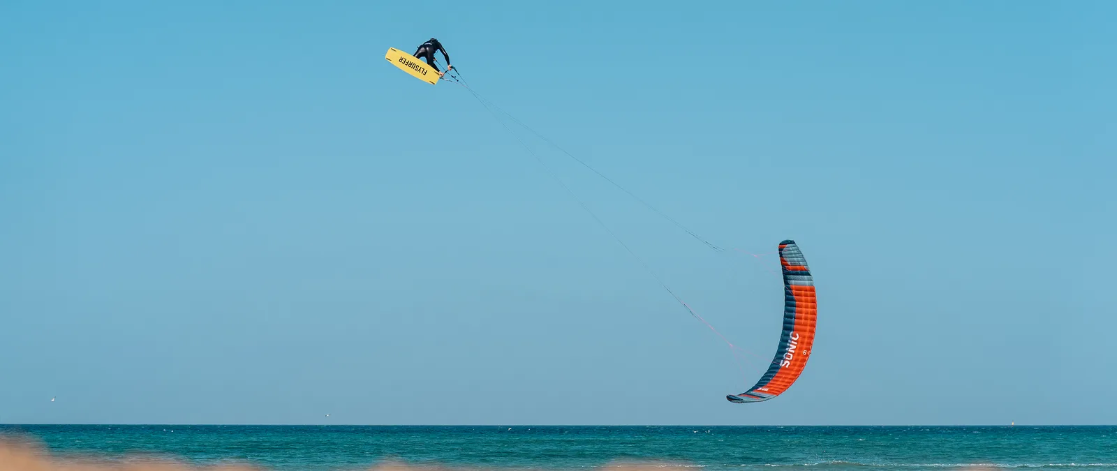 Kiter in salto sopra il mare, con il kite a cassone sotto di lui